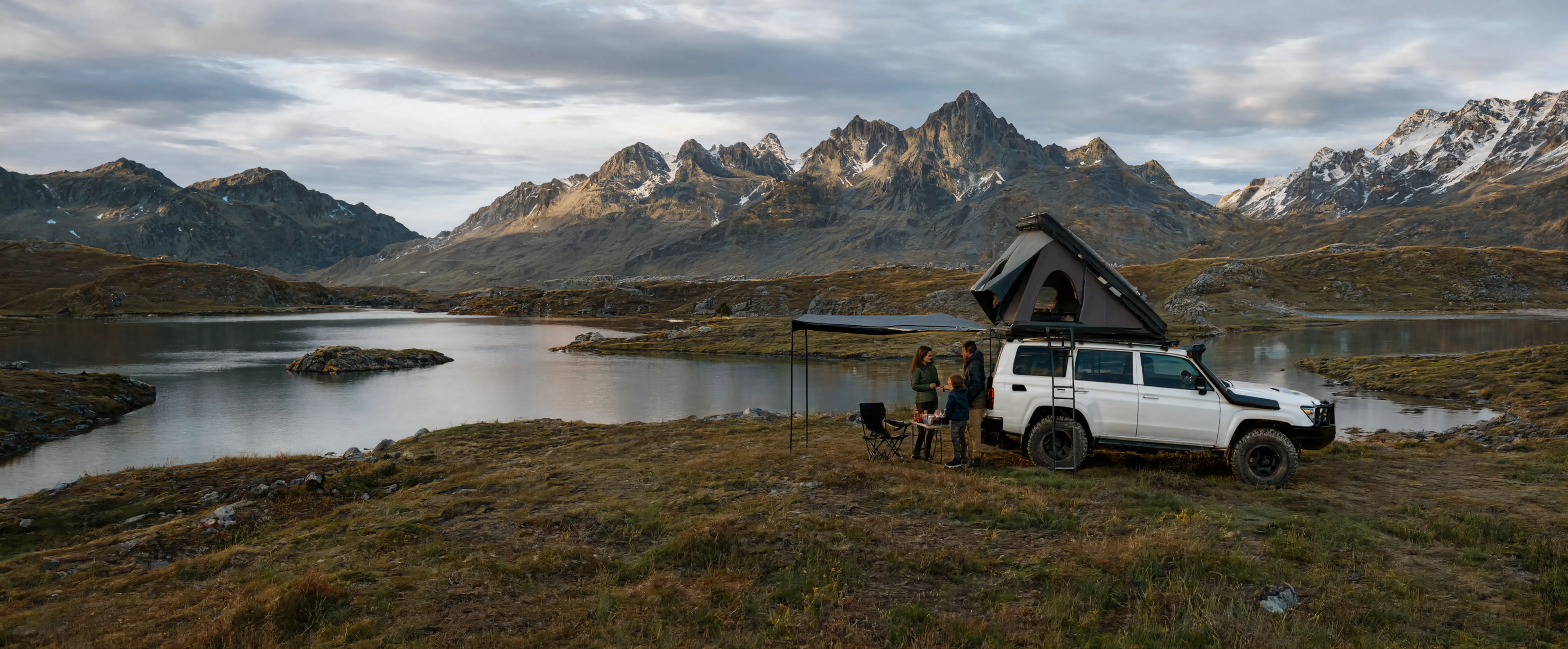 Tente de toit installée sur une voiture pour un campement au bord d'un lac en montagne